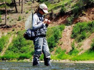 woman wearing fly fishing gear in vail valley